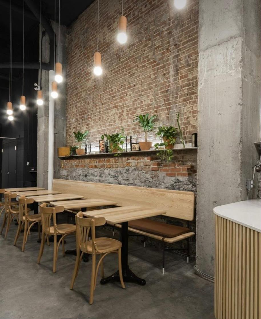 Interiorismo de espacio gastronómico con muro de ladrillo y mobiliario de madera